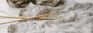 knitting needles on a light gray knitted piece